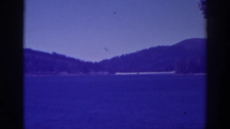 1938 Bucks Lake view with deep blue water, wooded mountain ridges, pale sky, and dark 8mm frame borders.