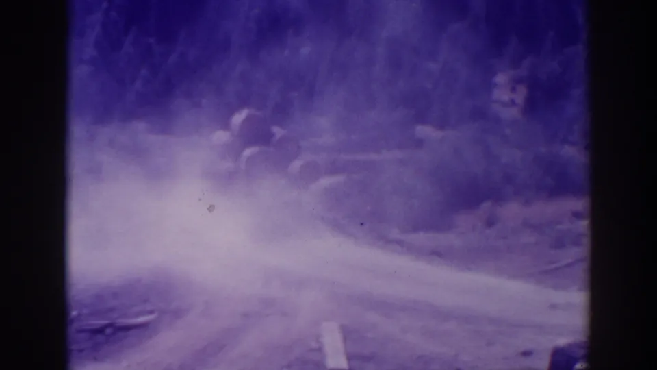 1938 home-movie frame of a dusty rural road in the Bucks Lake or Lake Tahoe area, with trees and strong purple film fading.