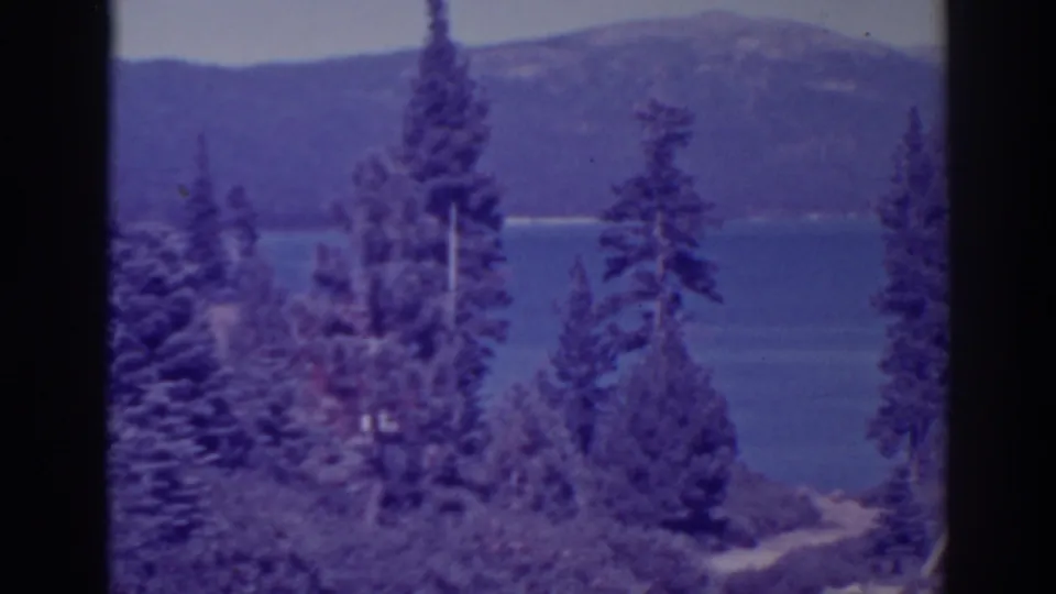 Near the end of the pan, pines and shrubs overlook Bucks Lake, with blue water and a wooded ridge visible beyond.