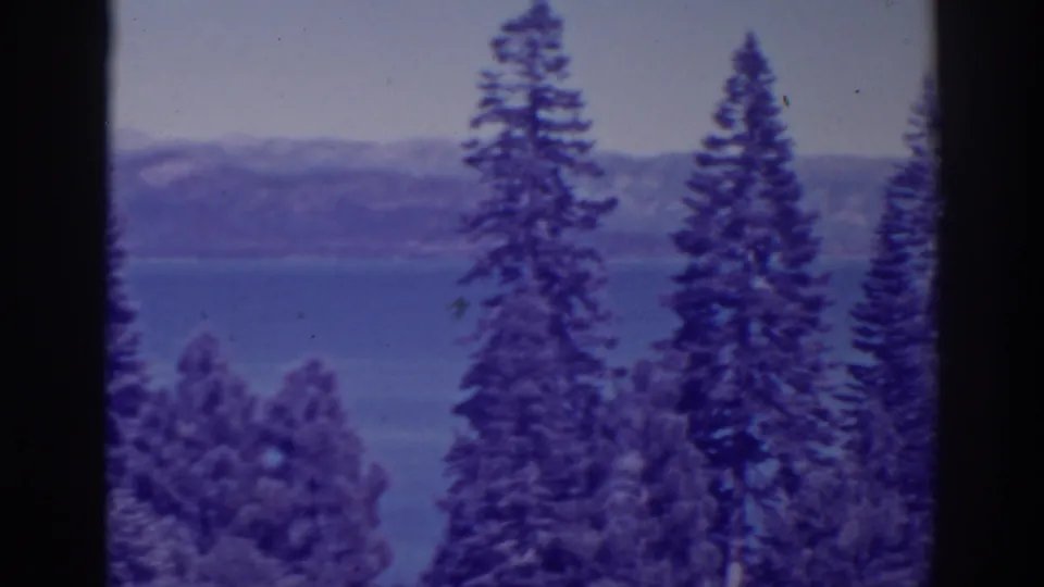 A 1938 8mm home-movie frame shows a forested overlook toward Bucks Lake and distant California mountain terrain.