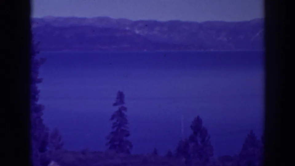 Bucks Lake, California, appears across a steady 8mm view with foreground pines, distant mountains, and soft purple-blue color.