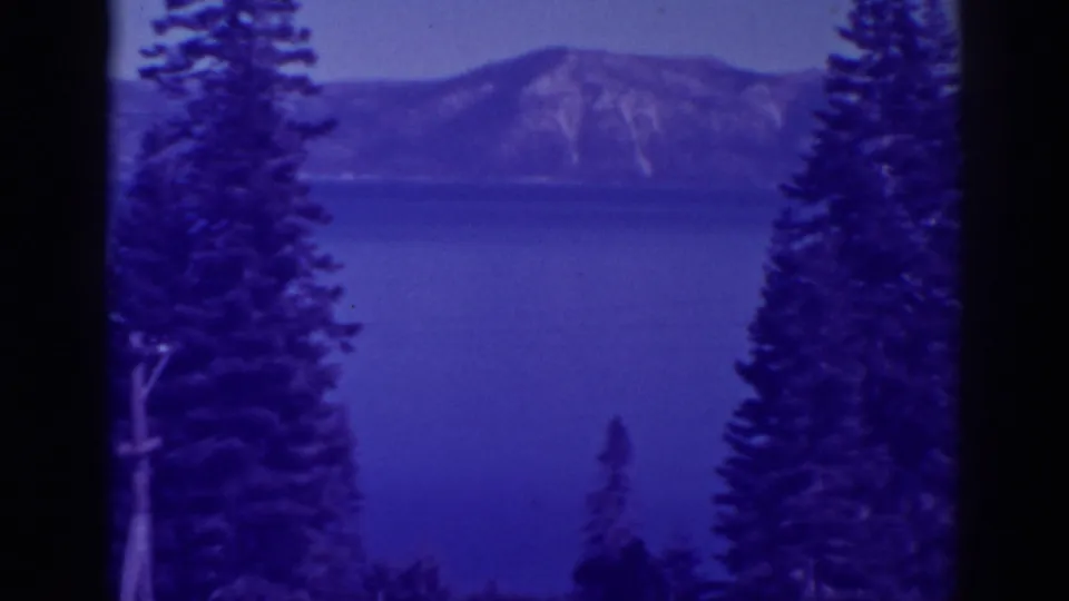 Bucks Lake, California landscape from 1938 metadata, showing blue lake water, distant mountains, and tall pines at the frame edges.