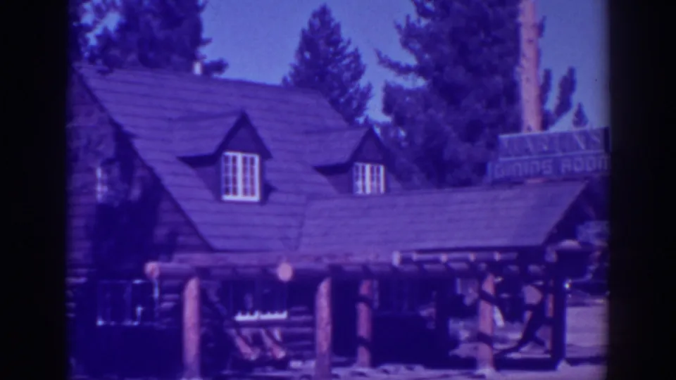 1938 home-movie frame of the El Dorado City log cabin restaurant, with roof dormers, log porch supports, and the Martin's Dining Room sign.