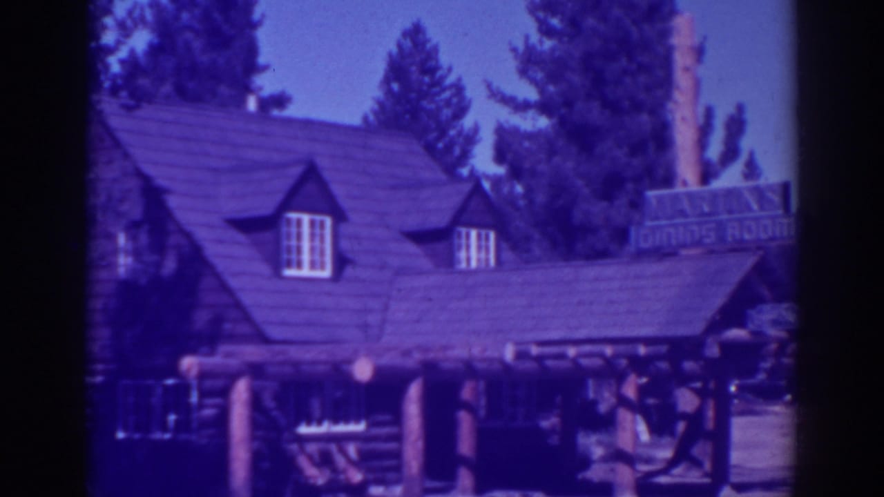 Rustic lodge exterior with shingled roof, log porch posts, dormer windows, trees, and a dining-room sign.