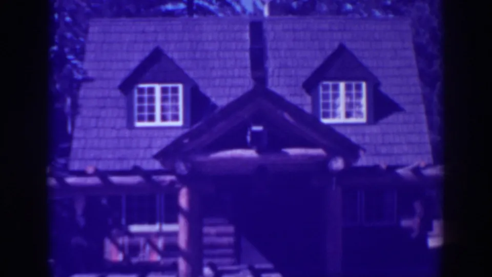 El Dorado City 1938 frame showing the upper facade of a rustic lodge, with twin dormers, white-trimmed windows, and heavy log construction below.