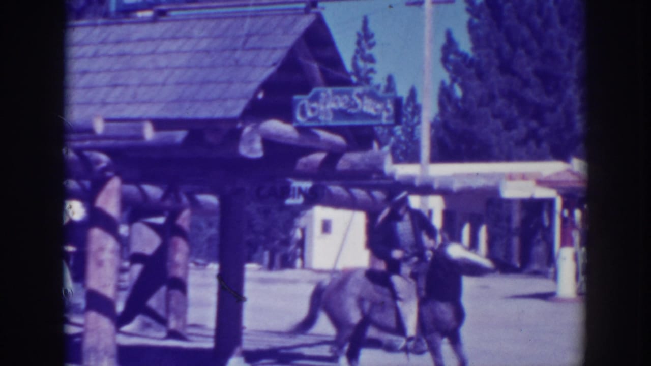 Horse and rider passing a rustic building with a Coffee Shop sign.
