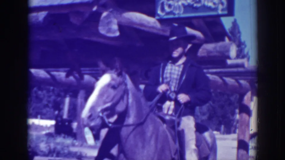 The rider remains mounted in front of the El Dorado City rustic shopfront, with strong color shift from the 8mm scan.