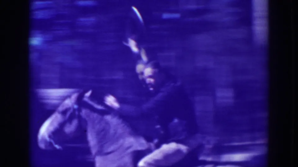 The rider, wearing dark clothing, lifts his hat while mounted, captured in a blue-purple shifted 8mm frame from the 1938 California home movie.