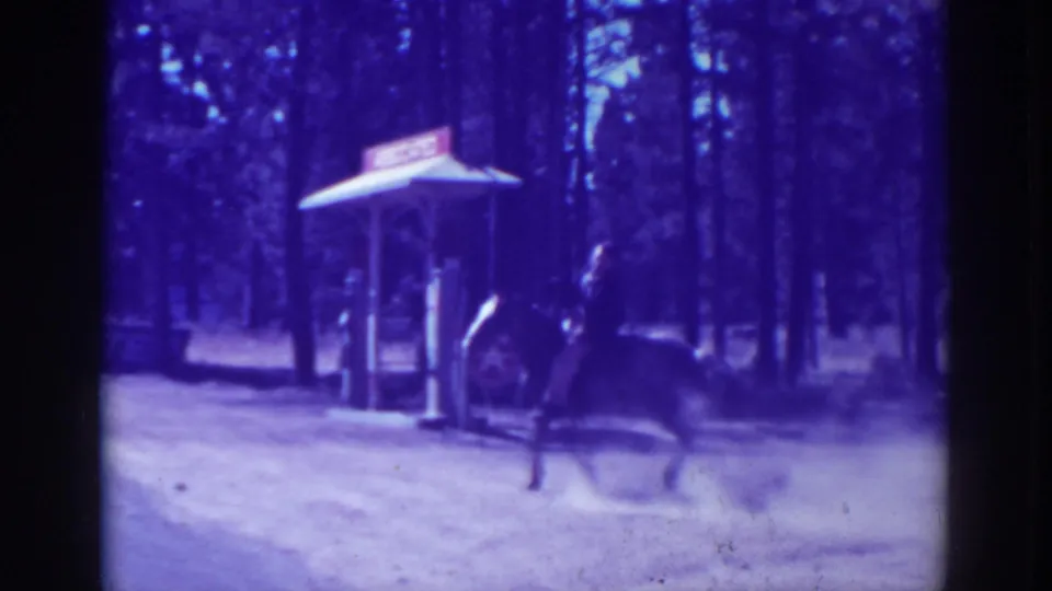 The rider continues past a small roadside structure on a dusty road in the wooded El Dorado City setting.
