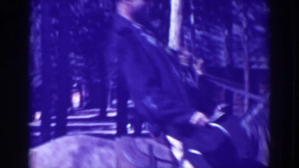 In 1938 El Dorado City, California footage, a man rides a light-colored horse past trees with a building partly visible behind him.