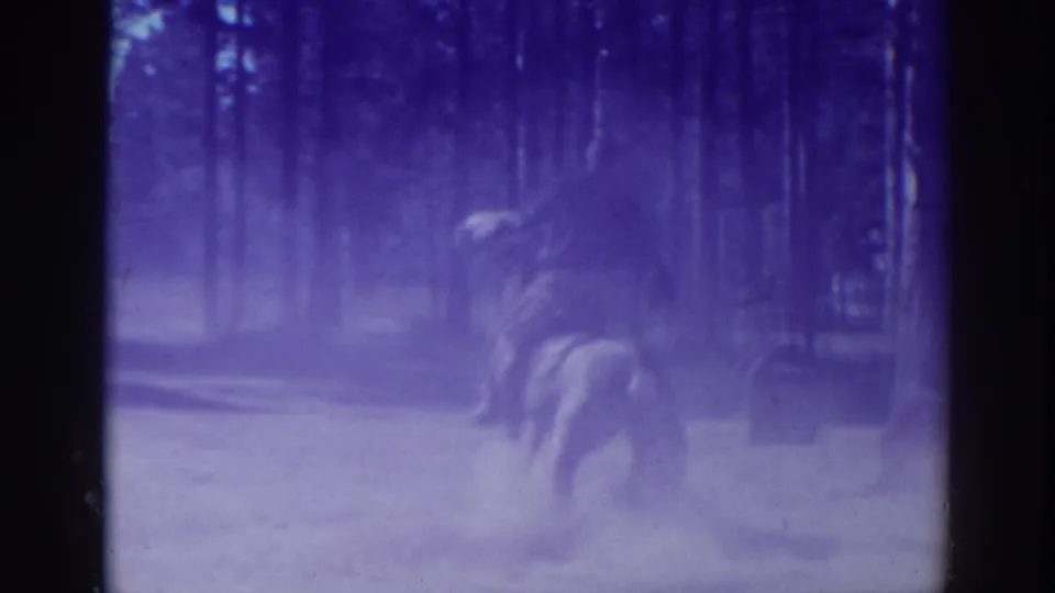The horse and rider move away through a dusty wooded area in the El Dorado City home-movie footage.