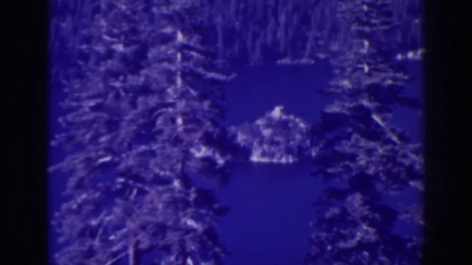 A second 1938 Emerald Bay frame shows the same tree-framed lake view with a small island or rocky point beyond the branches.