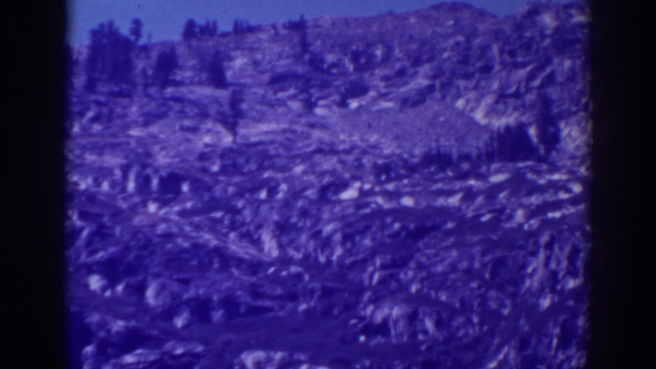 Rugged ridge and shallow valleys seen through blue-tinted 8mm film.