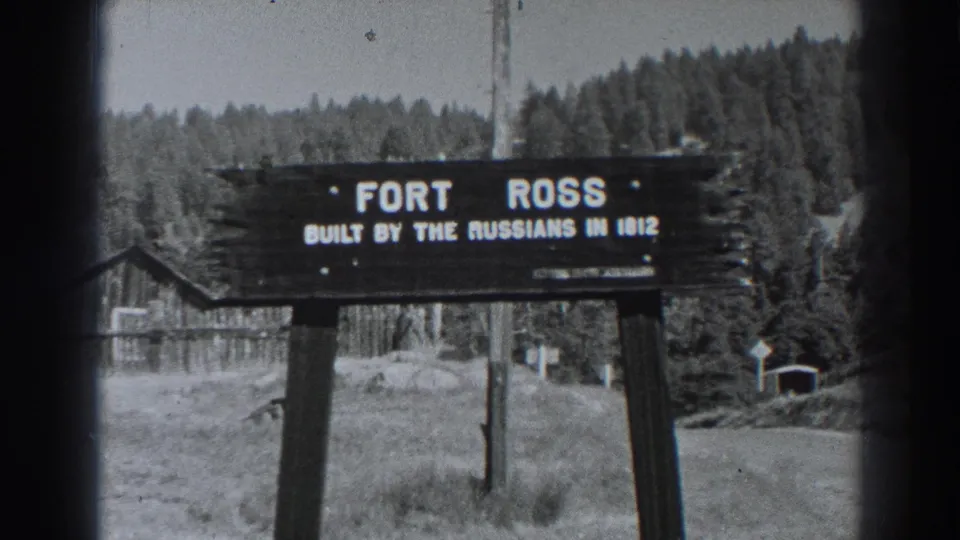 Visitor-shot 1938 view of the Fort Ross sign, with the 1812 wording visible and historic-site structures in the background.