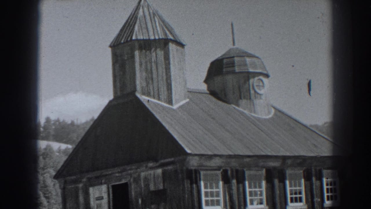 Black-and-white frame of a wooden building with roof towers and a cross.
