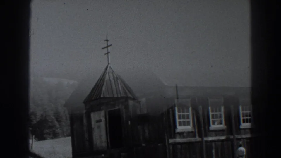 Fort Ross, California 1938 frame showing the wooden church facade with steeple, doorway, windows, fence, trees, and distant hills.