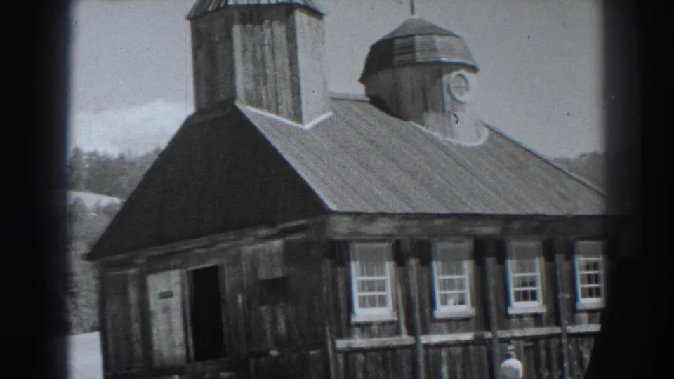 Fort Ross, California 1938 frame showing a wider exterior view of the wooden church, its sloped roof, windows, doorway, and domed tower.