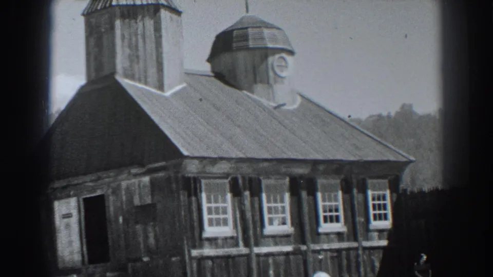 Fort Ross, California 1938 frame showing the church exterior from a slightly lower angle with windows, roof, domed tower, trees, and fence.