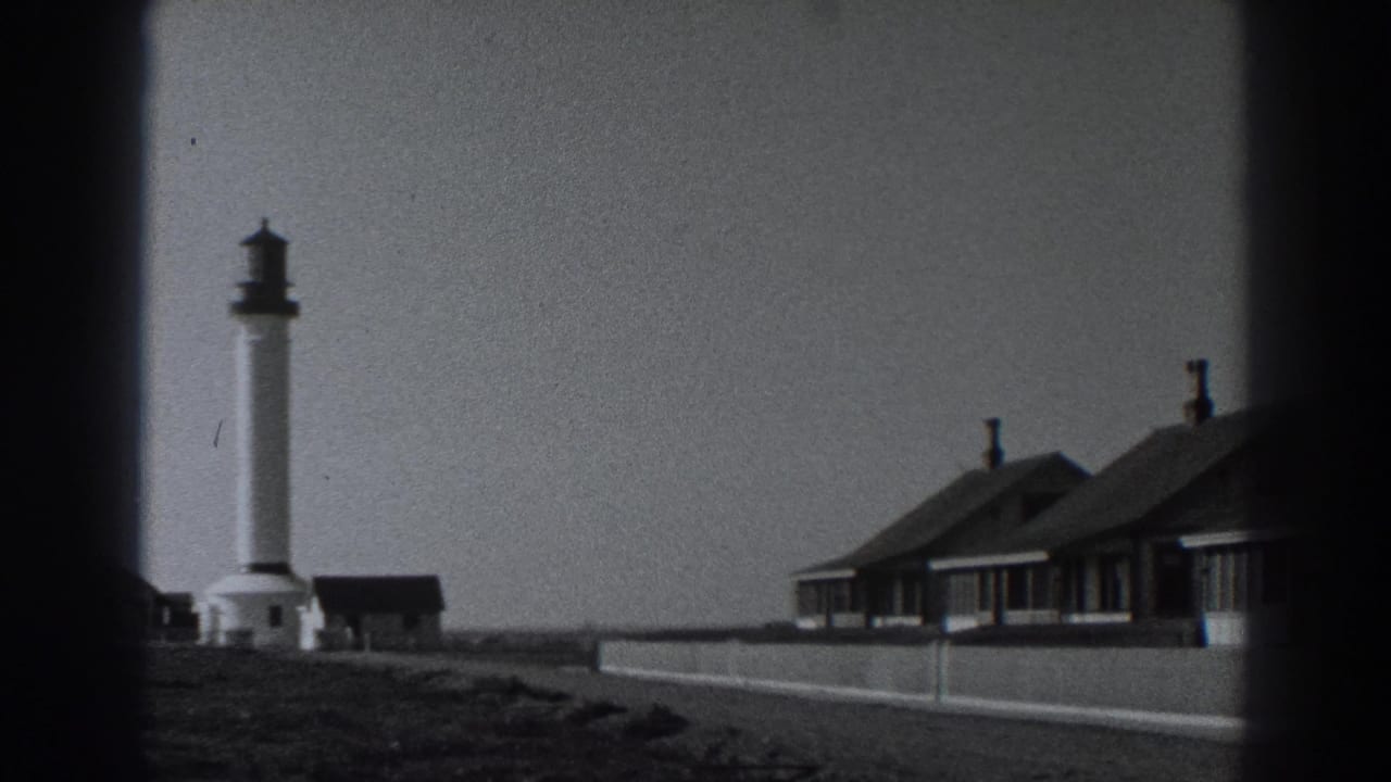 Fort Ross, California home-movie frame showing the lighthouse and adjacent beachside cottages during a slow rightward pan.