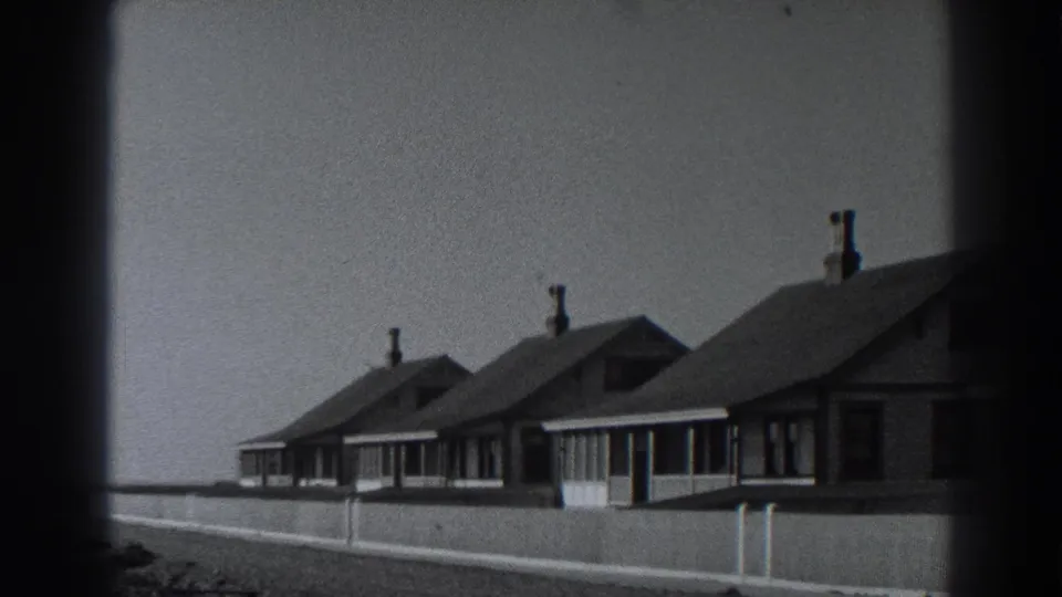 Fort Ross coastal cottages appear in soft black-and-white 8mm footage, with porch windows and chimneys visible.