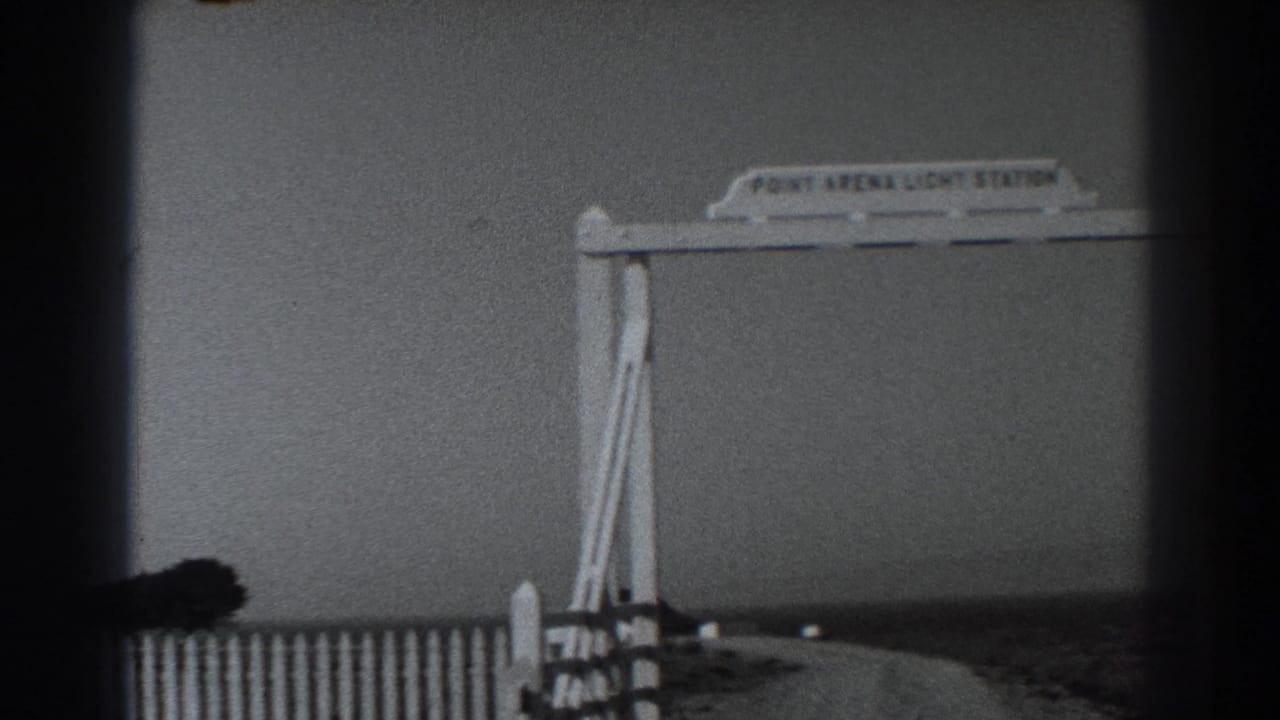 The sign and fence remain in view as the 8mm frame catches a dark foreground obstruction during the slight camera movement.