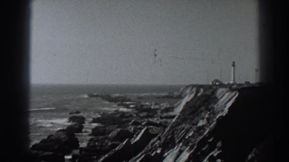 1938 Fort Ross-area home-movie frame showing a lighthouse on a rocky point above waves and shoreline.