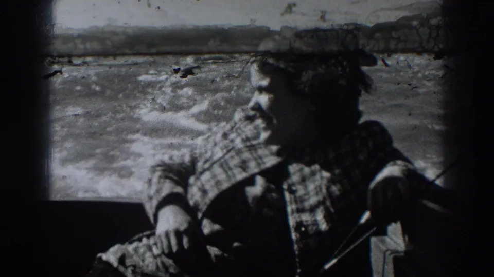 A woman in patterned outerwear sits in a boat near choppy water in the 1938 home-movie footage.