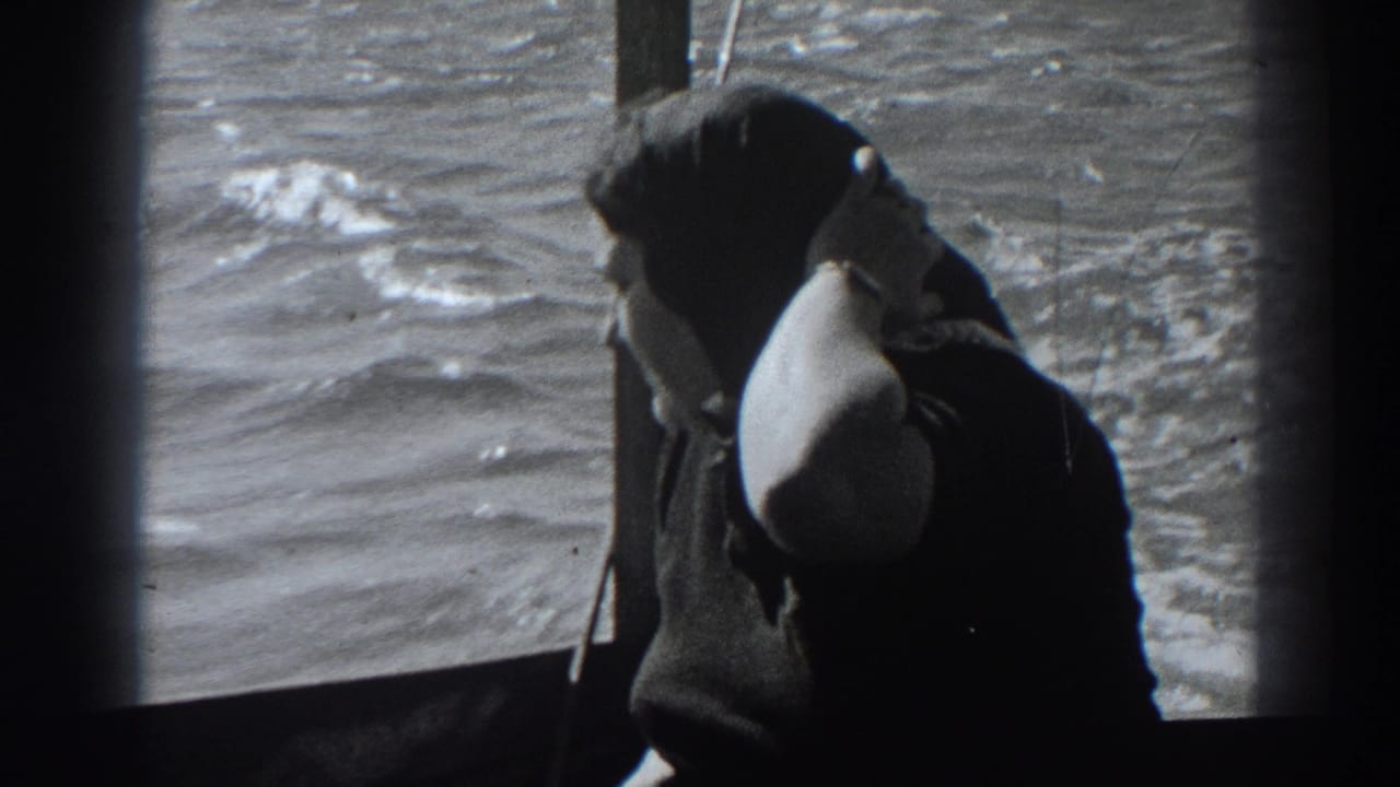 Woman in a dark coat adjusts her scarf while seated by a boat window with water outside.