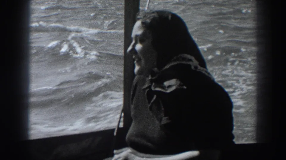 The woman sits in profile inside the boat, smiling toward the cabin area with Fort Ross water visible beyond the window.