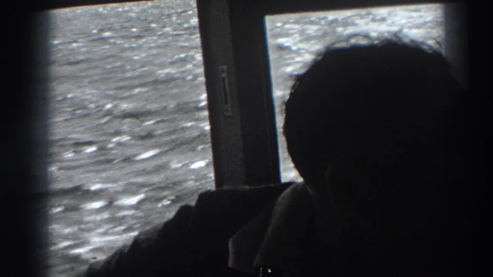 The man remains mostly in silhouette inside the boat, with bright choppy water visible through the window in this 1938 California home-movie frame.