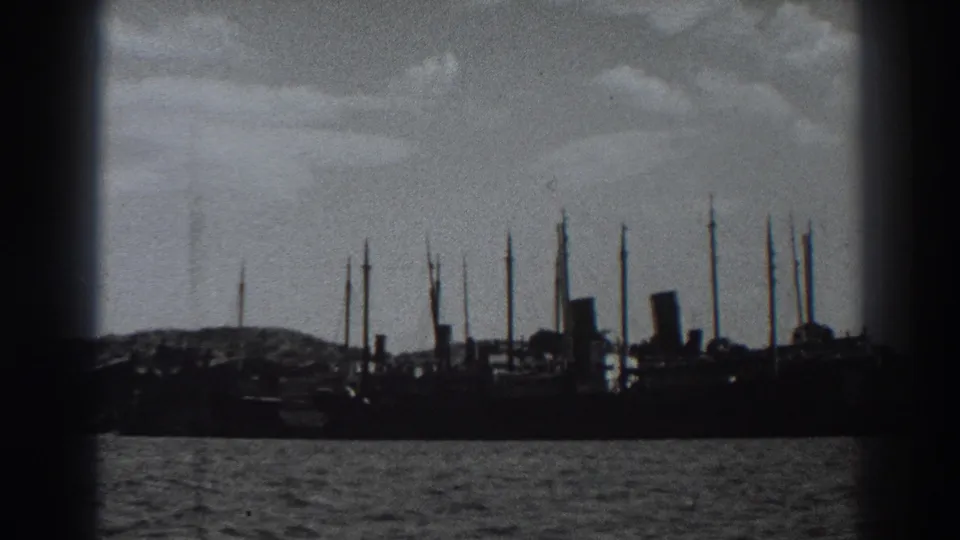 Late-1930s Fort Ross home-movie frame showing a docked ship, masts, water ripples, shoreline, and visible film-gate borders.
