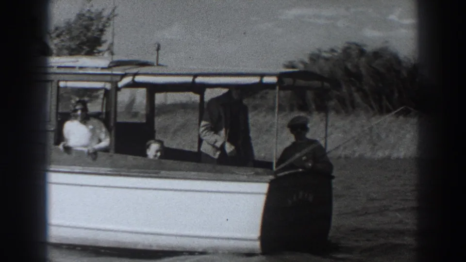 Close Fort Ross frame showing passengers aboard the white motorboat, including a person in a white shirt facing the camera near the cabin.
