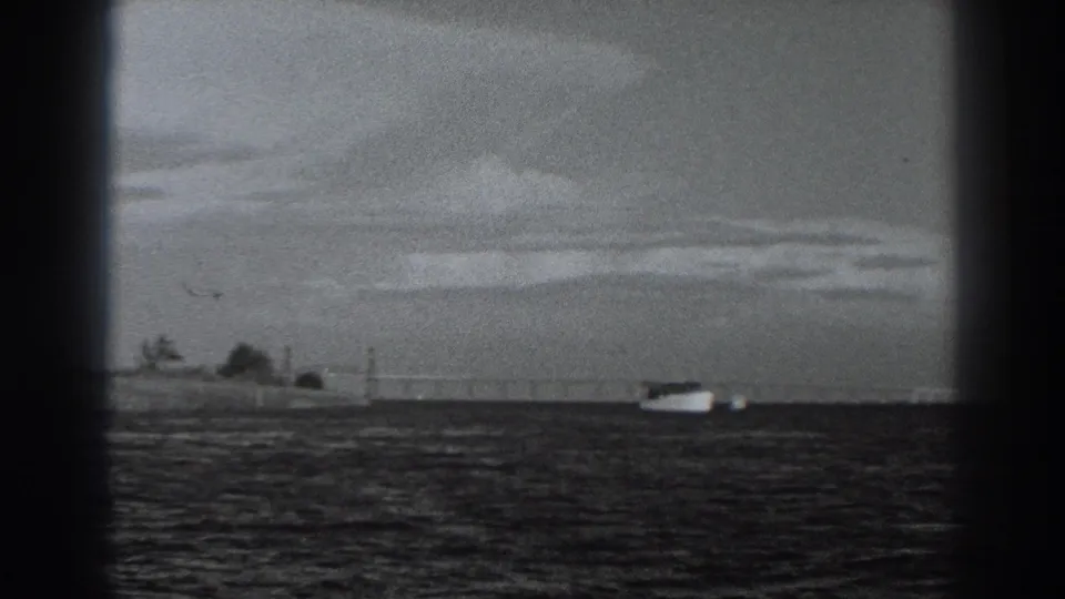 1938 Fort Ross coastal home-movie frame with a small boat on open water, distant shore details, and dark frame-edge borders from the film scan.