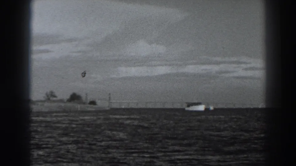 1938 Fort Ross-area home-movie frame showing a distant white boat on dark water beneath layered clouds.