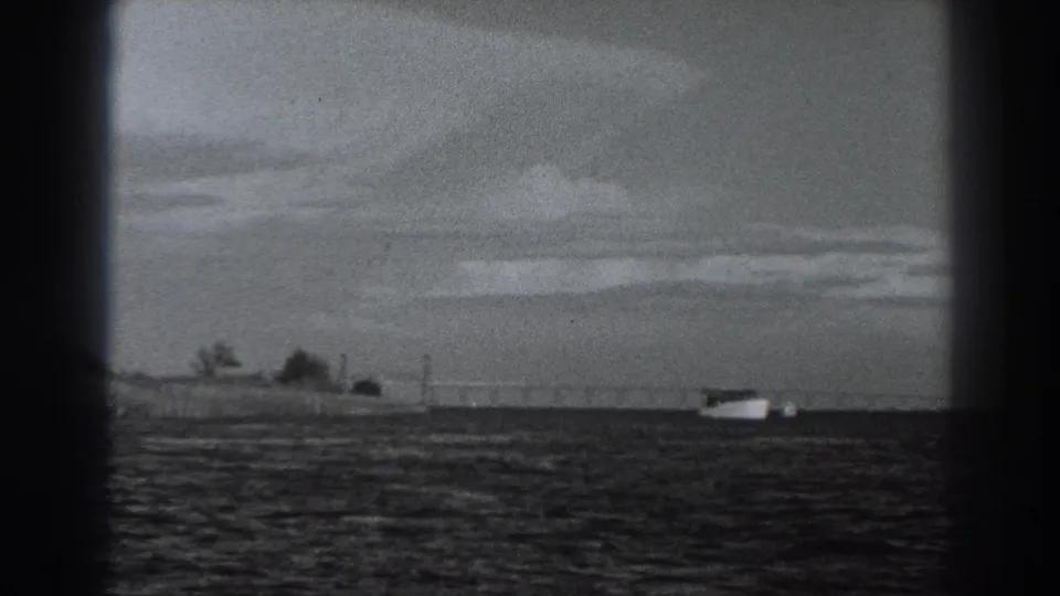 Distant boat and low Fort Ross-area shoreline appear through grainy 8mm framing, with no people visible.