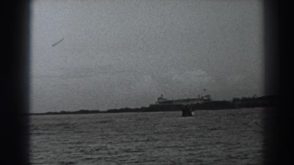 Fort Ross 1938 home-movie frame showing a distant ship across open water, with low shoreline and visible 8mm borders.