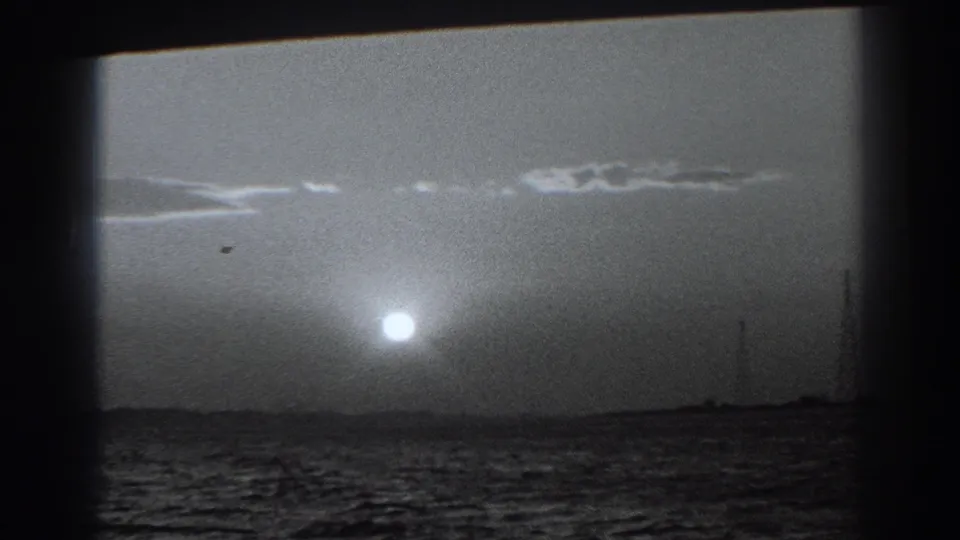 1938 Fort Ross-area home-movie frame showing the low sun above choppy coastal water and a silhouetted shoreline.