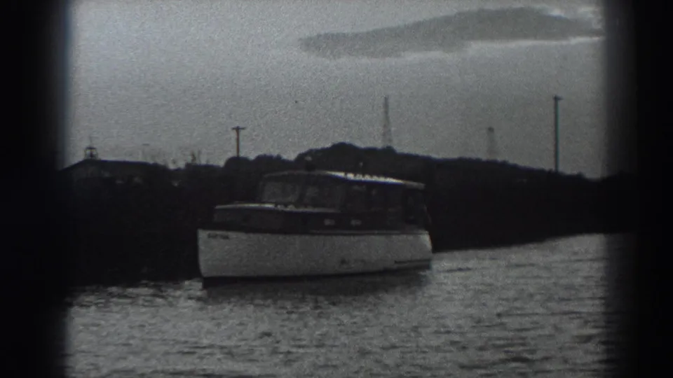 A small boat appears near the Fort Ross-area shoreline in a grainy 1938 8mm coastal home-movie frame.