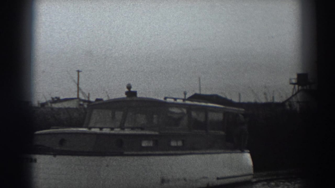 Motorboat centered on the river with shoreline structures in the background.
