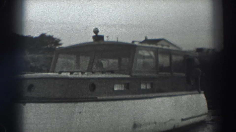 A 1938 Fort Ross frame shows the motorboat's bow and cabin as a man holds onto the side of the vessel.
