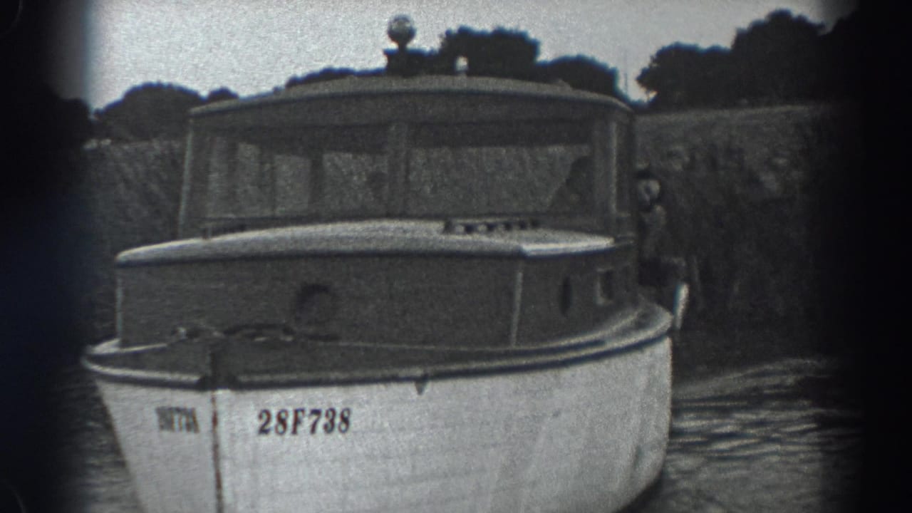 Cabin motorboat seen from the front with a person partly visible at the side.