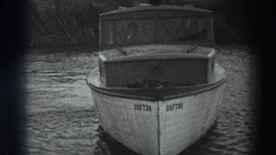 1938 Fort Ross home-movie frame showing a small cabin motorboat with bow rail and registration number on a river.