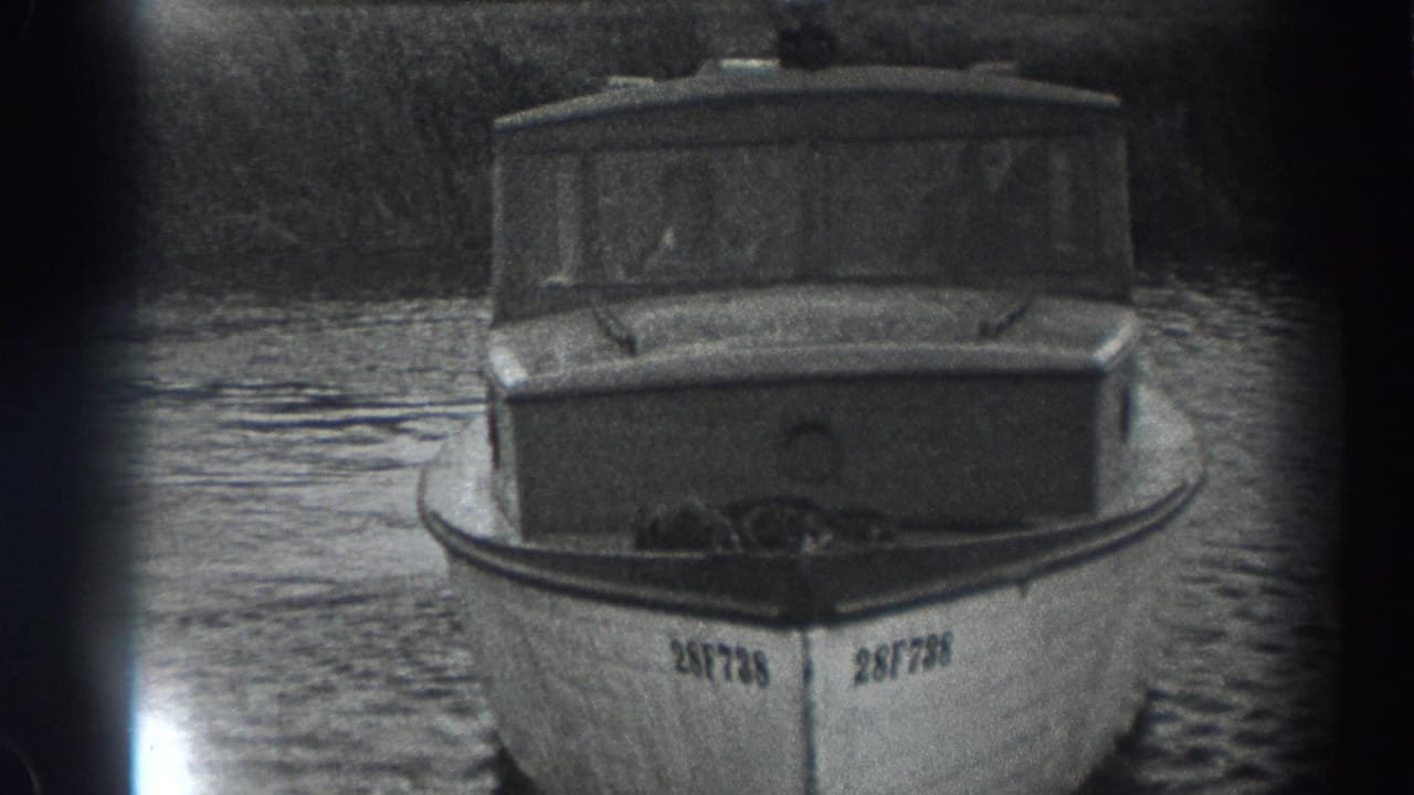 Cabin boat centered on water with registration number visible at the bow.