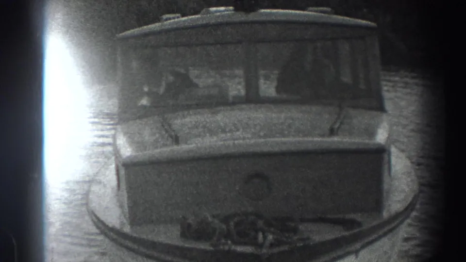 1938 8mm home-movie frame showing a small cabin motorboat floating on calm water with soft monochrome grain.