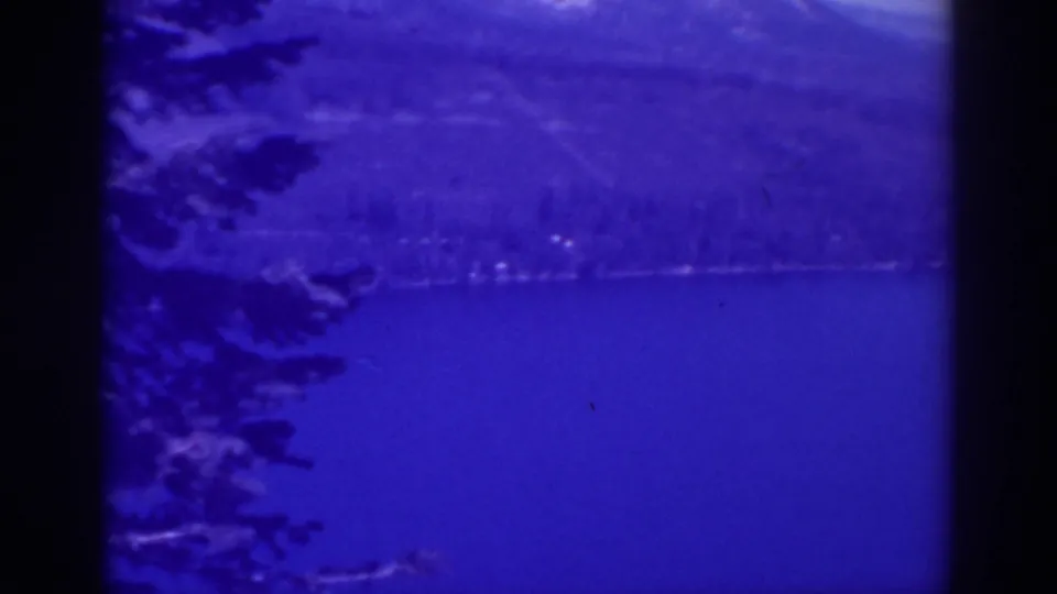 Lake Tahoe, California, in blue-shifted 1938 8mm footage, showing calm water, a far wooded shore, and mountain ridges.