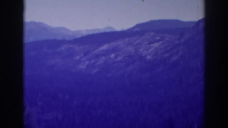 1938 8mm home-movie view of layered High Sierra mountain ridges, likely near Lake Tahoe, with strong purple color aging.
