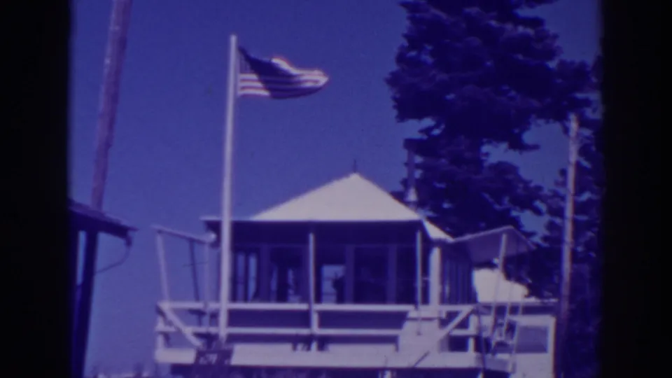 1938 8mm Lake Tahoe lookout station view with an American flag, porch railings and tall pines.