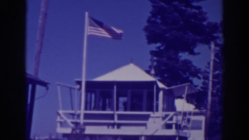 Final 1938 Lake Tahoe-area frame of the wooden lookout station, flagpole and pine trees in aged 8mm color.