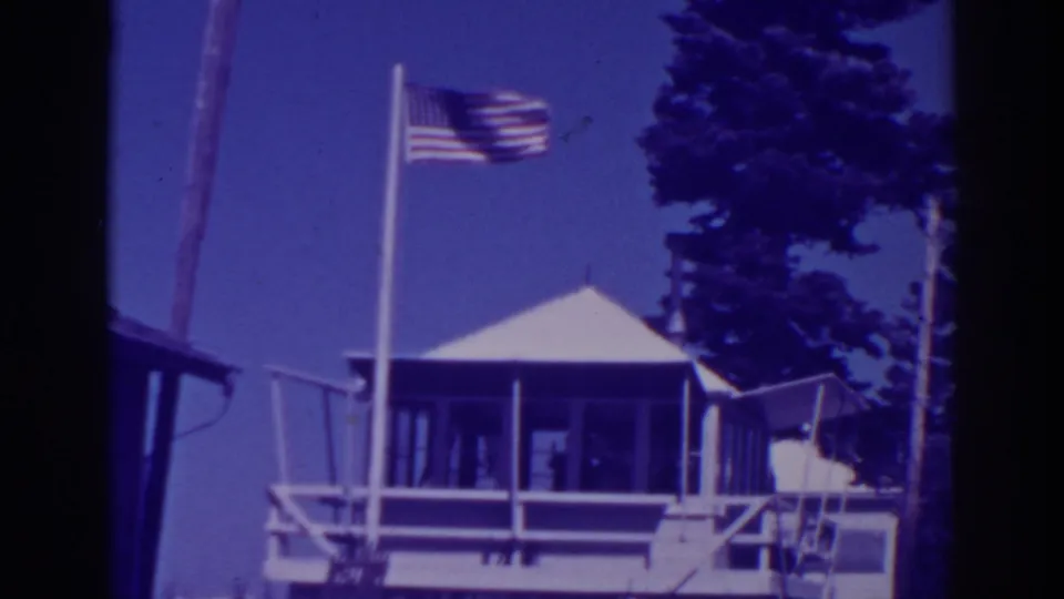 Visitor-shot 1938 Lake Tahoe view of Martin's Lodge with the American flag blurred by motion in the wind.