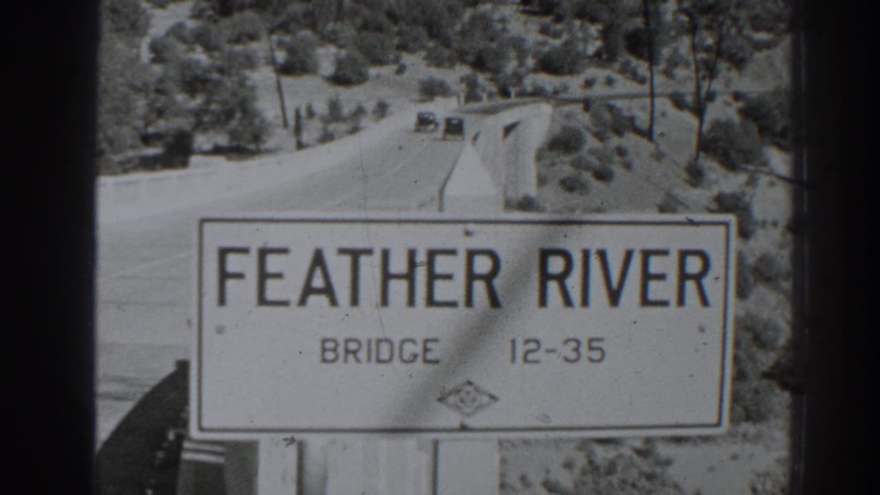 Feather River Bridge sign with road and small cars visible in the distance.